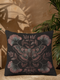 A square decorative pillow featuring an intricately detailed Luna moth in faded rose pink, slate blue and dusty terracotta colors on a black background. The moth is centered in a symmetrical arrangement with ginkgo-inspired leaves and botanical elements surrounding it.